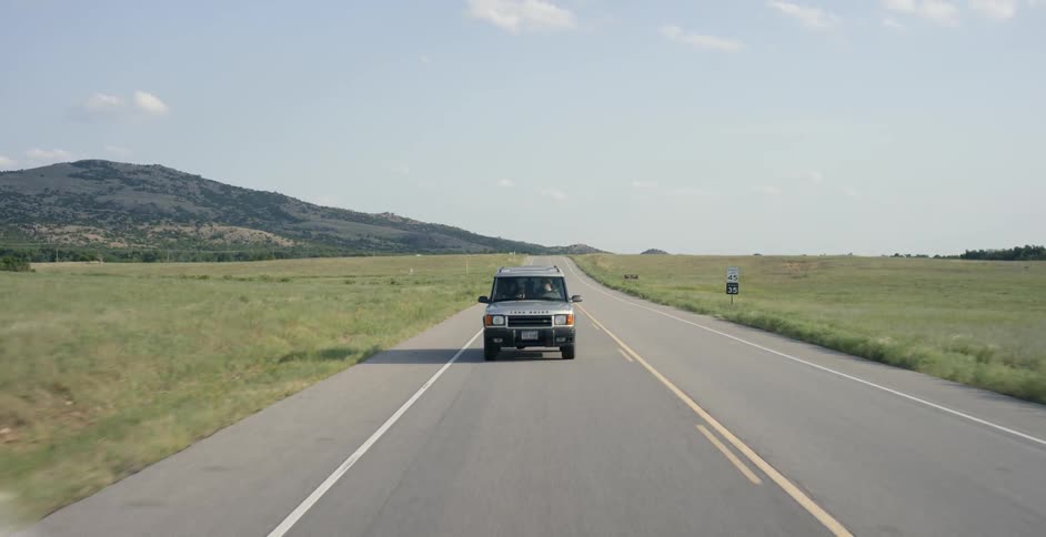 A gray vehicle drives down a road during the day