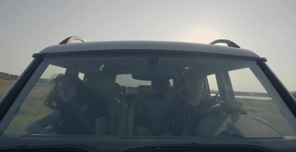 Woman and two men ride in a jeep