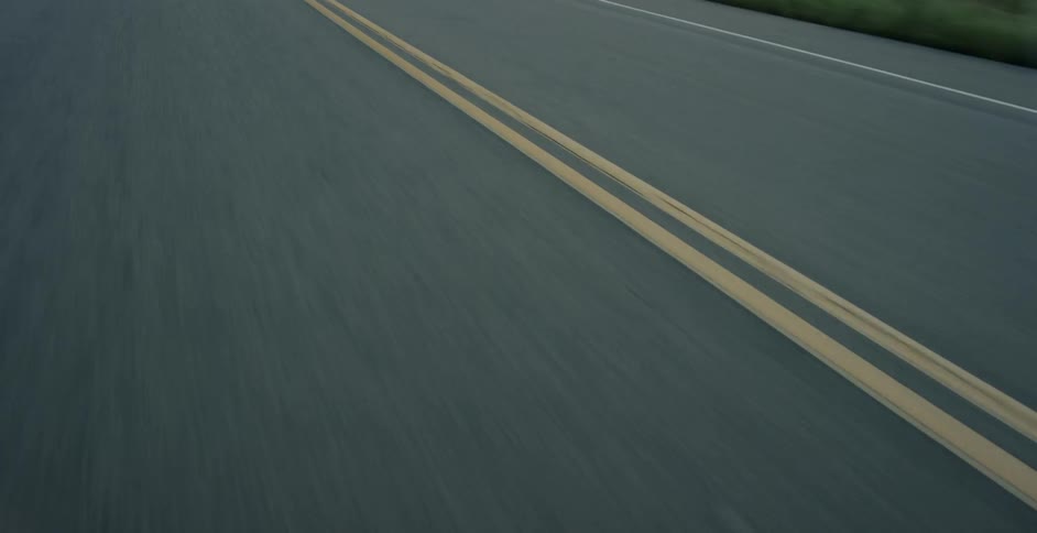 A vehicle drives on a paved road