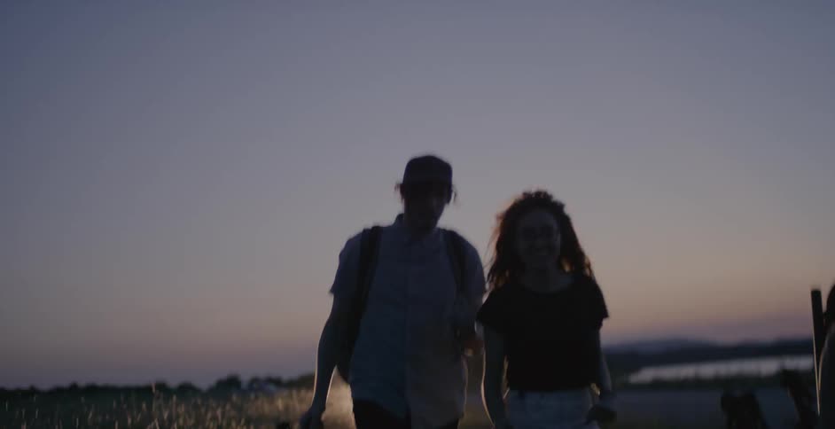 A group of people carrying things and walking in some weeds along a coast