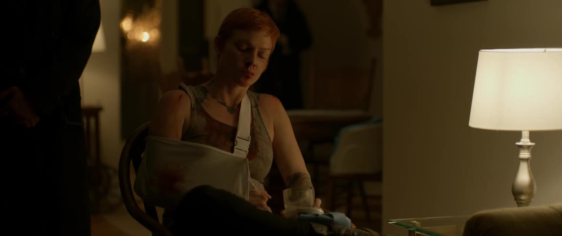 A woman is sitting with an arm brace and glass of liquor