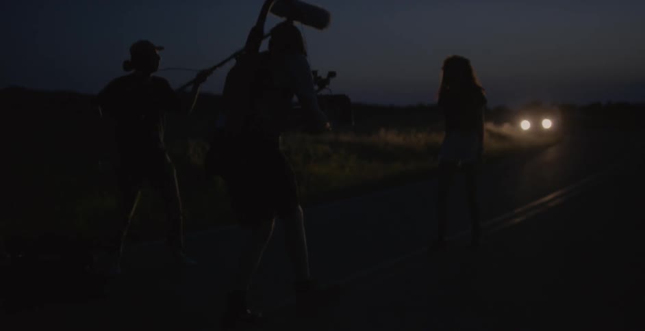 Group of people holding camera equipment outside in the dark