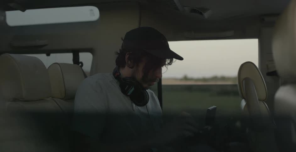 A man in the backseat of a car looking at a large camera