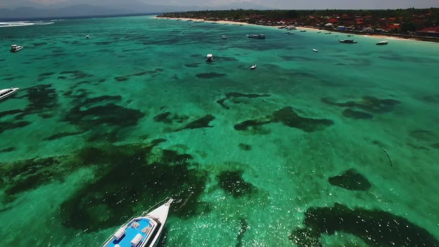 Boats float just off the coast on a sunny day
