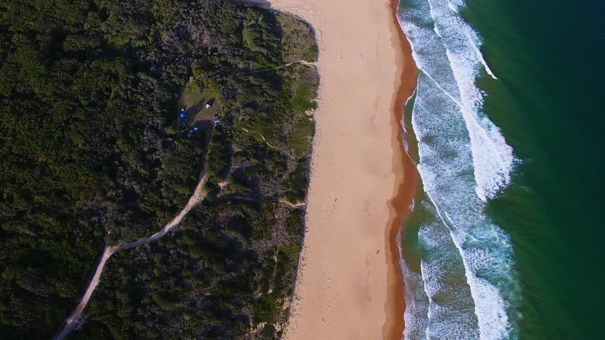 Aerial view of a beach and water splashing to shore
