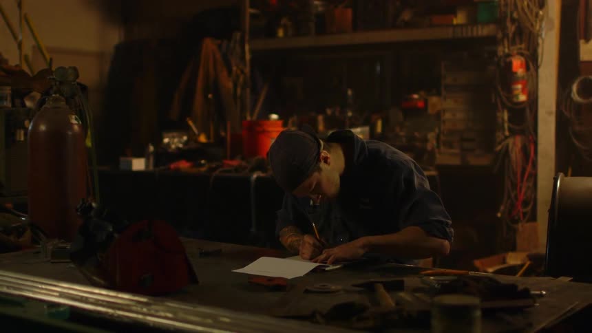 Man writing on a piece of paper in a dimly lit room