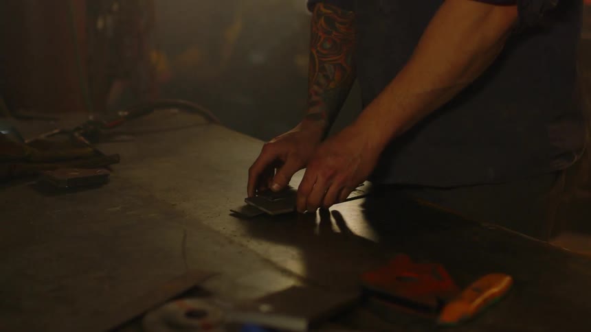 A man puts some pieces of metal on a workbench
