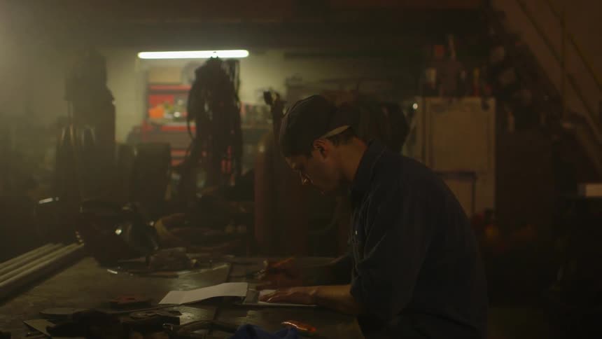 A man is working in a shop writing in a notebook