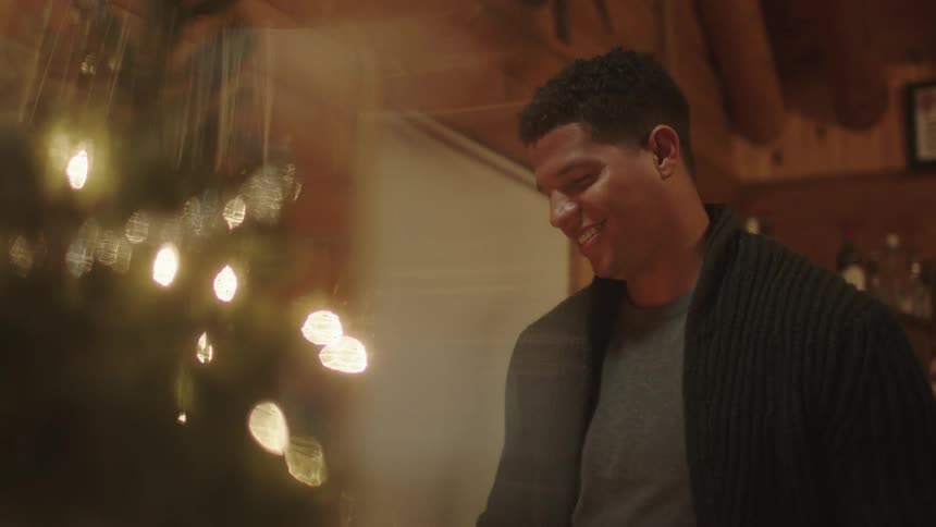 Smiling man stands next to a christmas tree