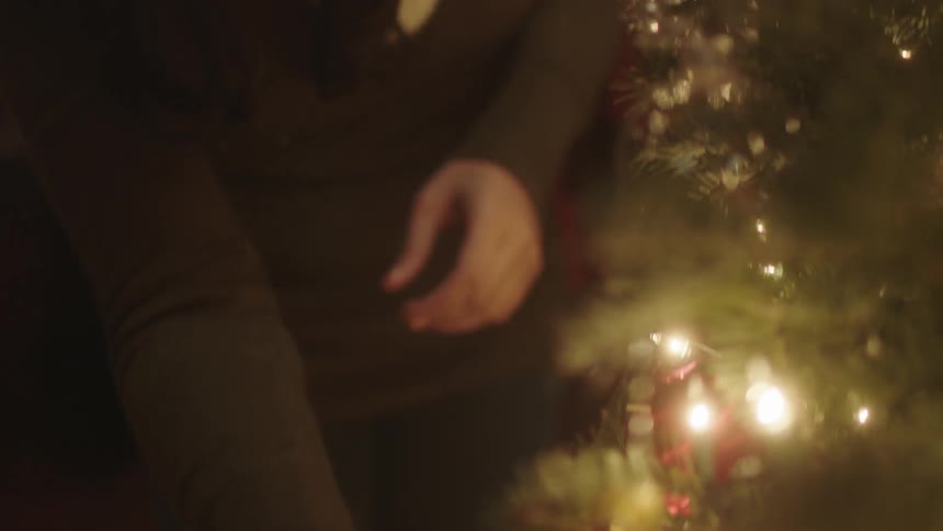 A christmas tree is almost decorated by a woman