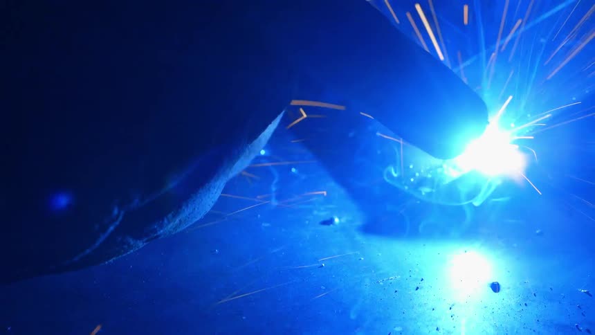 A welding tool results in sparks and smoke flying through the dark air