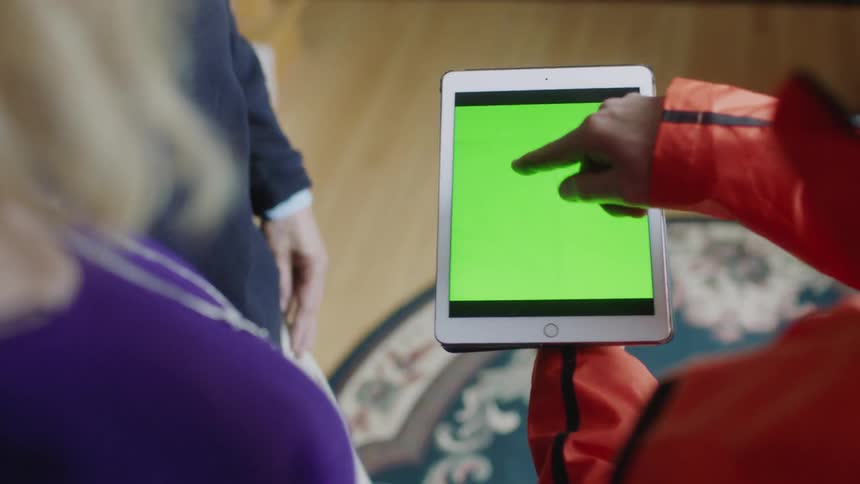 Man pointing to tablet with two other people watching