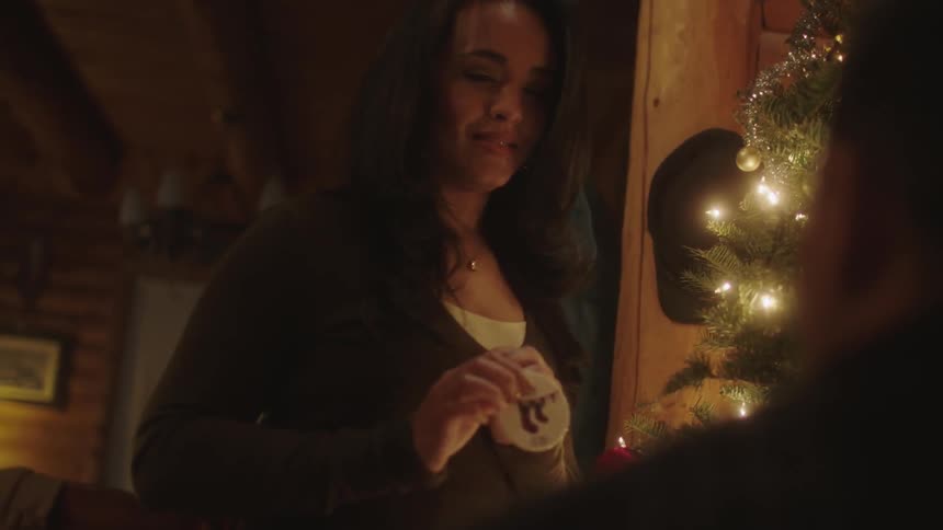 A man and a woman in a house and she is showing him an ornament