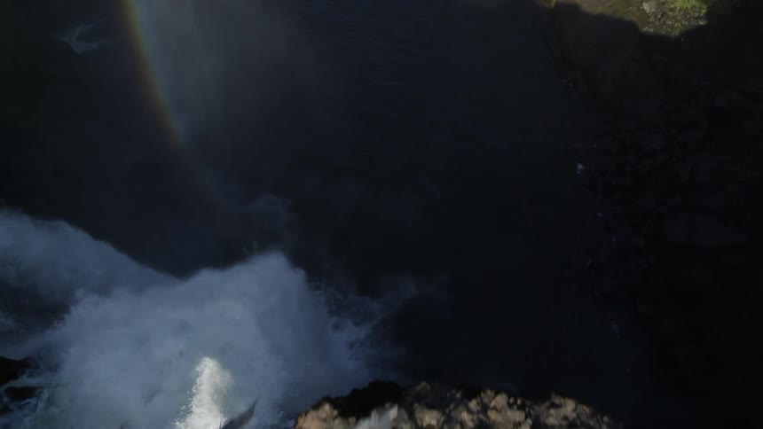 Following the flow of water as it plunges off the edge of a cliff into a pool below