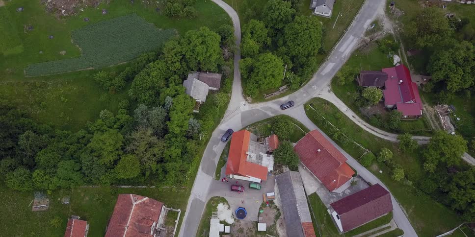 An overhead view of cars driving down a road with houses all around