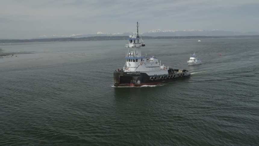 A tugboat sailing fast in the water as it returns to harbor