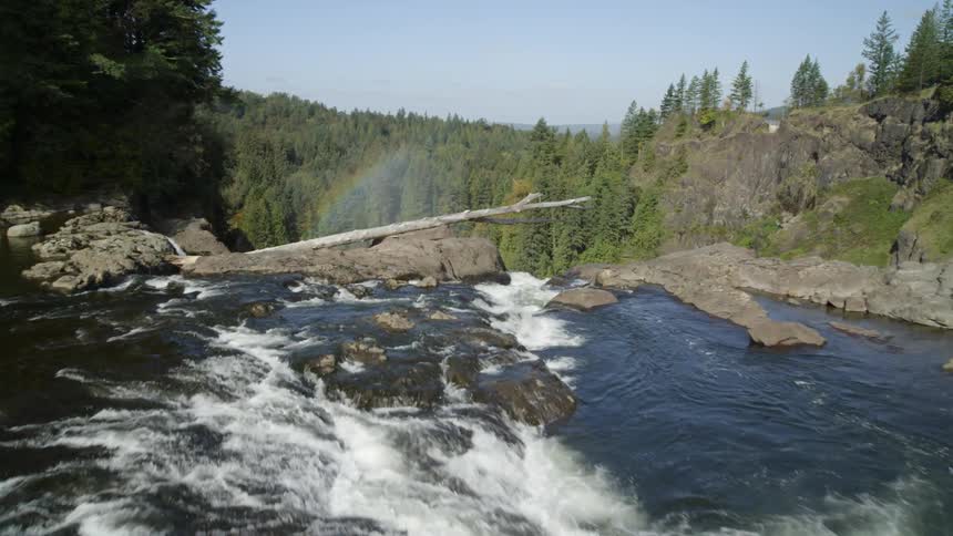 Calm water leads to a spillway and waterfall gushing over a cliff