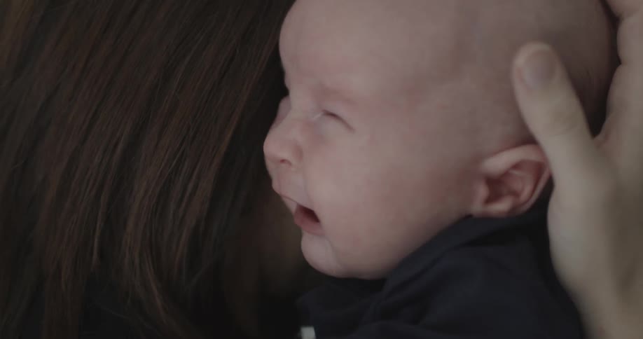 A woman holds a crying baby over her shoulder