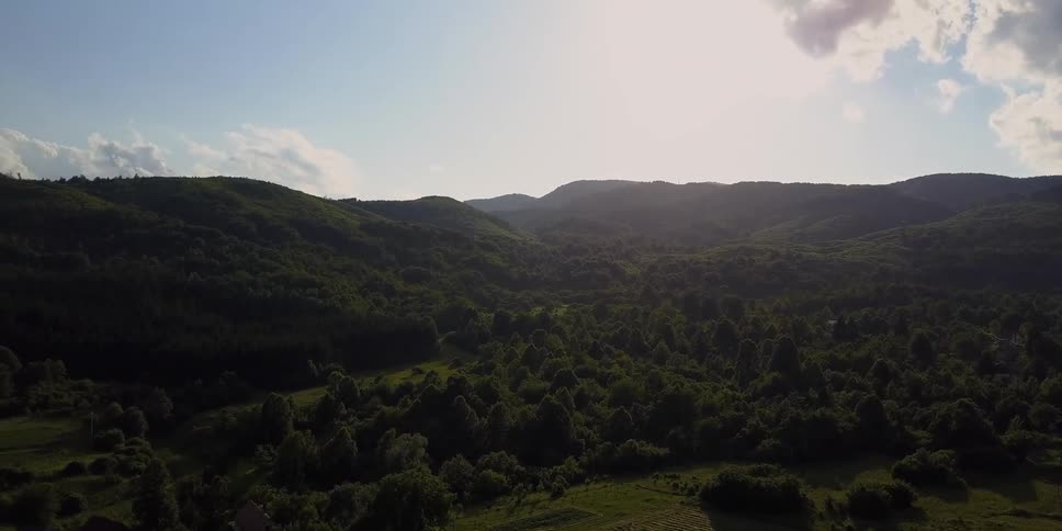 The sun is casting rays through the clouds in a mountainous region