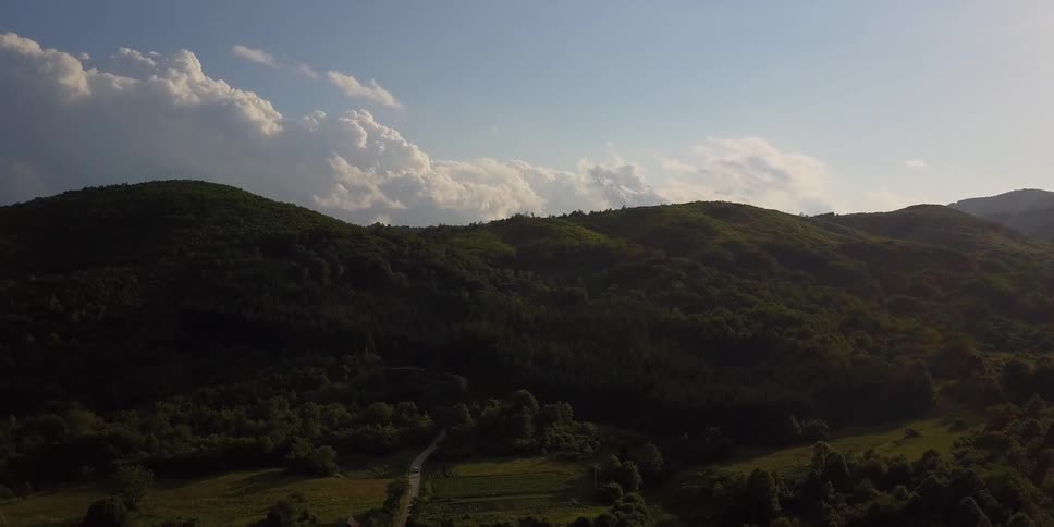 Clouds float over a hill covered with trees