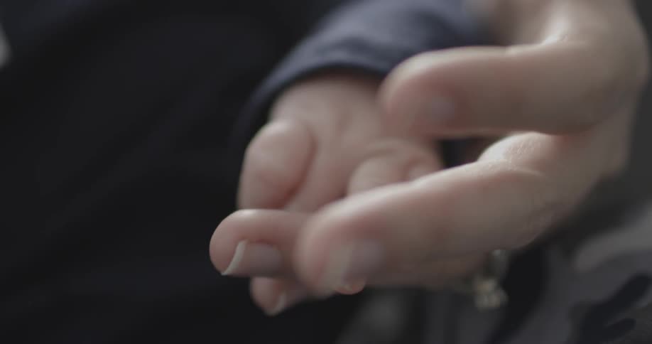 A woman is holding a baby's hand in hers