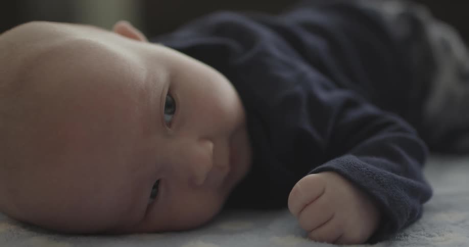 An infant lays on his stomach and tries to lift his head