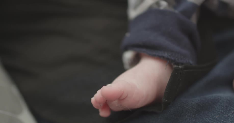 A baby sitting on someone's lap and showing it from the knee down