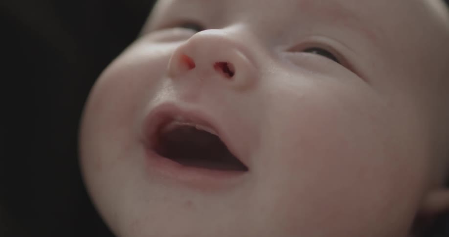 An infant smiles and opens its mouth