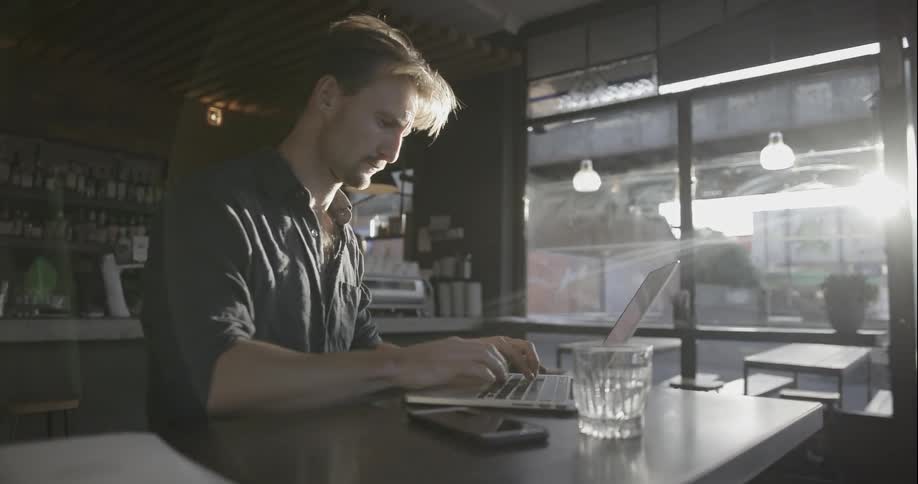 A man is in a cafe using his laptop