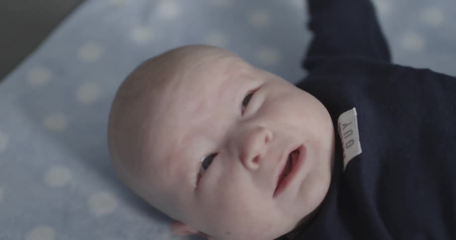 Crying baby laying on a blanket