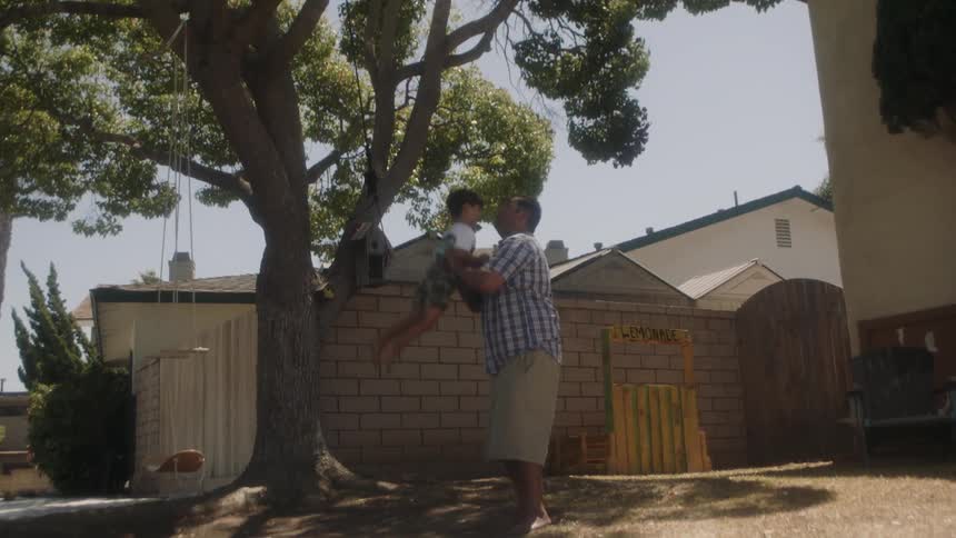 Man lifting child over his head in the backyard