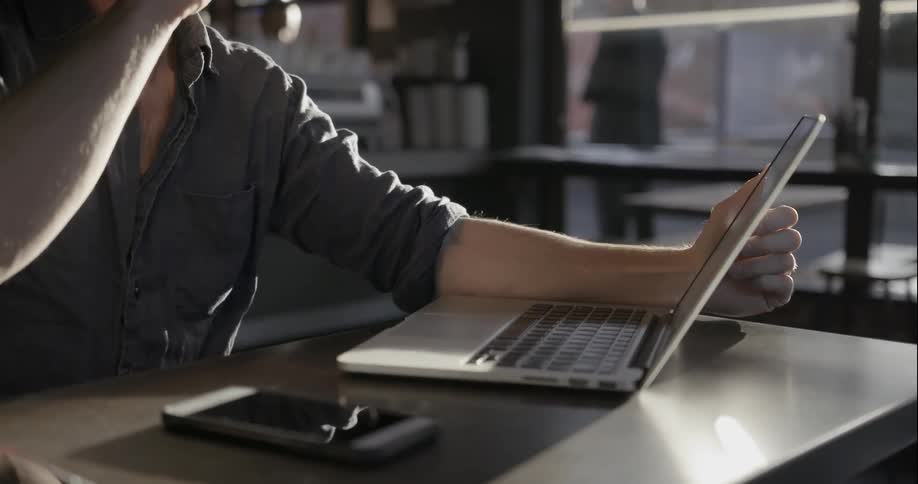 Man looks at a laptop and drinks from a glass
