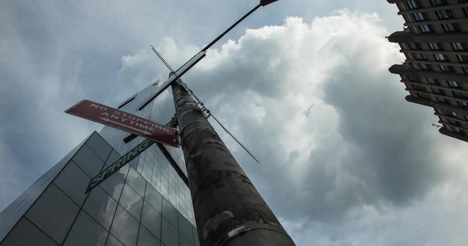 A tall building has clouds passing fast overhead