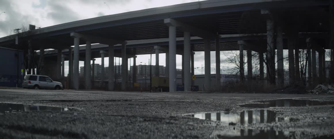 Vehicle driving under a divided-highway underpass on a cloudy day