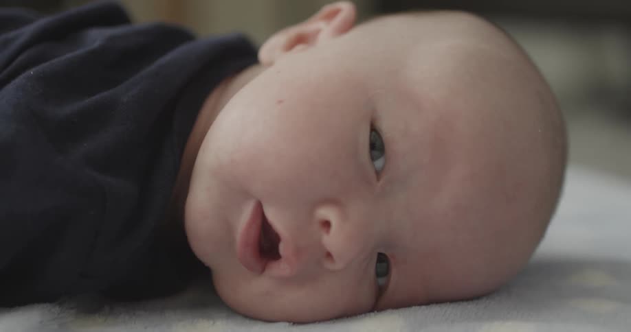 A baby is smiling and lying down