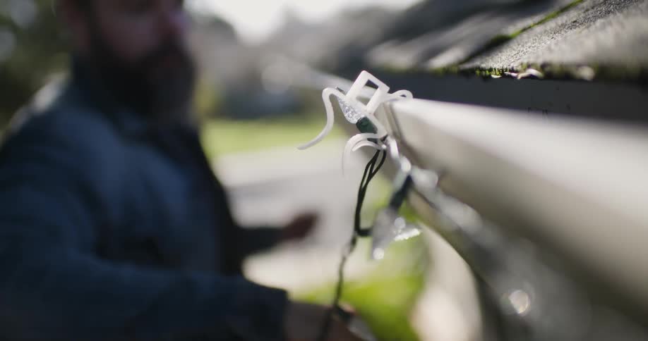 A bearded man strings up christmas lights