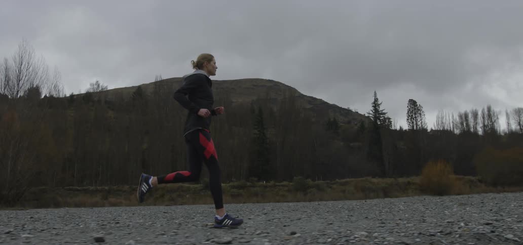 Woman runs over a stony road on a cloudy day
