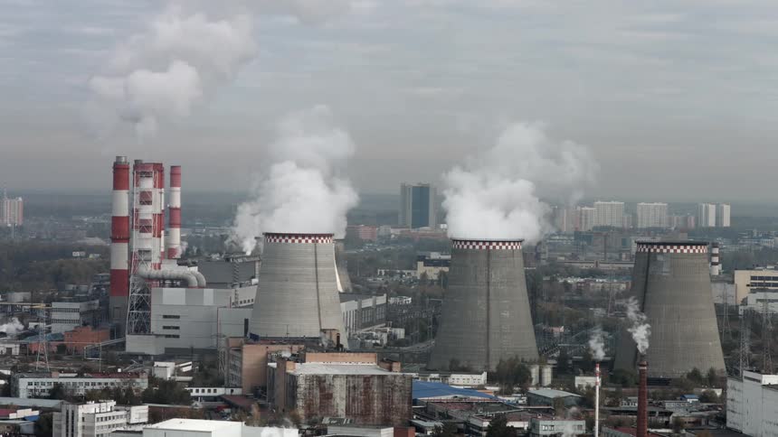 A row of industrial chimneys give off smoke into the sky