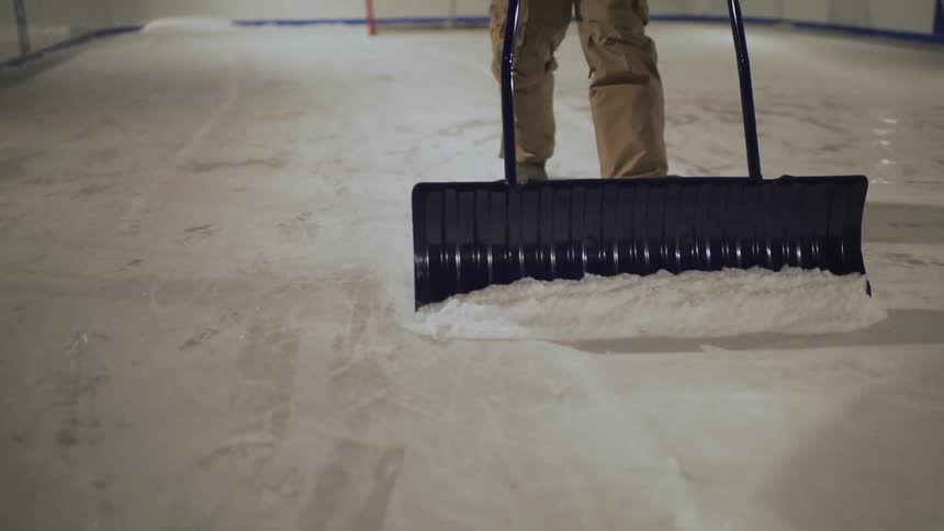 A man is cleaning the ice in an outdoor ice-rink
