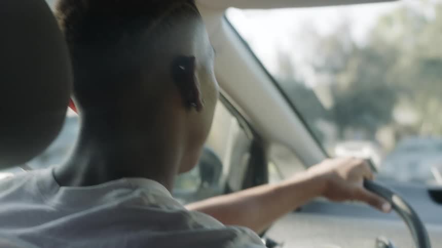 A young man in a white shirt is driving