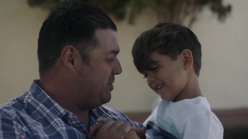 A man is holding his child talking and laughing