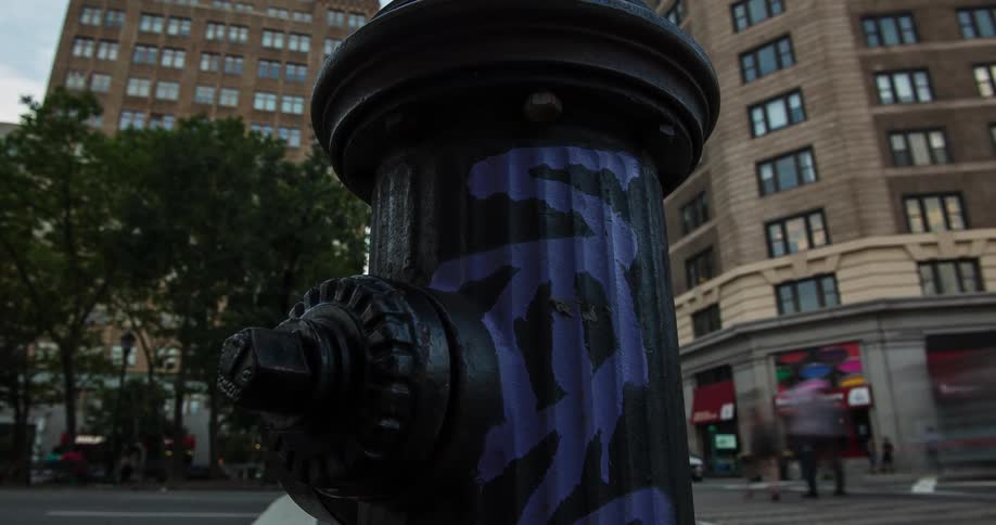 A fire hydrant sits on a busy city intersection