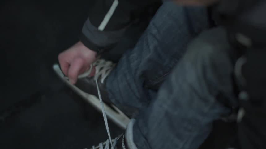 A man laces up an ice skate