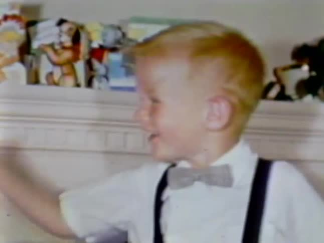 A boy laughs and waves to the side