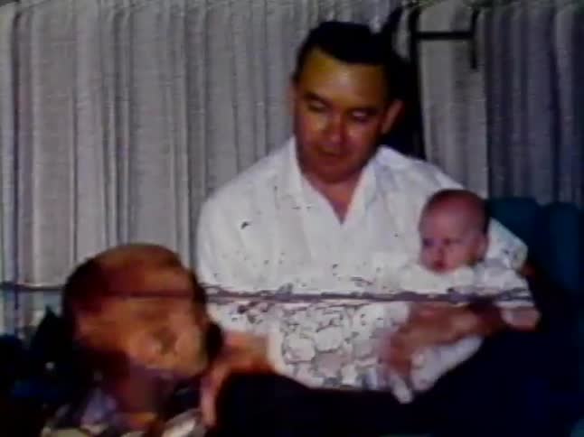 Man holding a baby and talking to a little boy