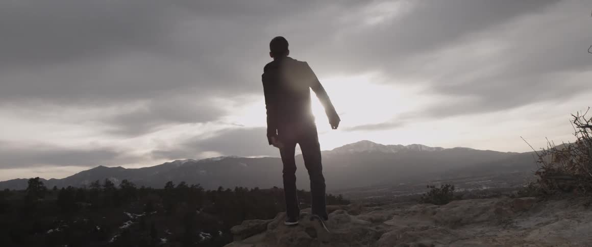 A man walks over the mountain top to look at the sky ahead