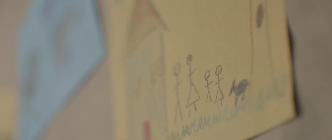A children's drawing hangs on the wall