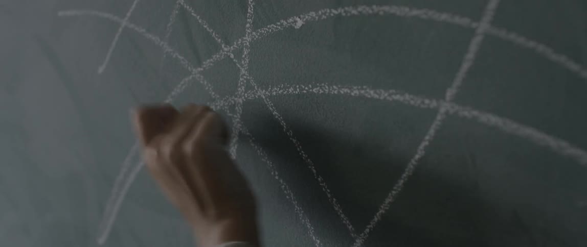Hand scribbling on a chalkboard with chalk