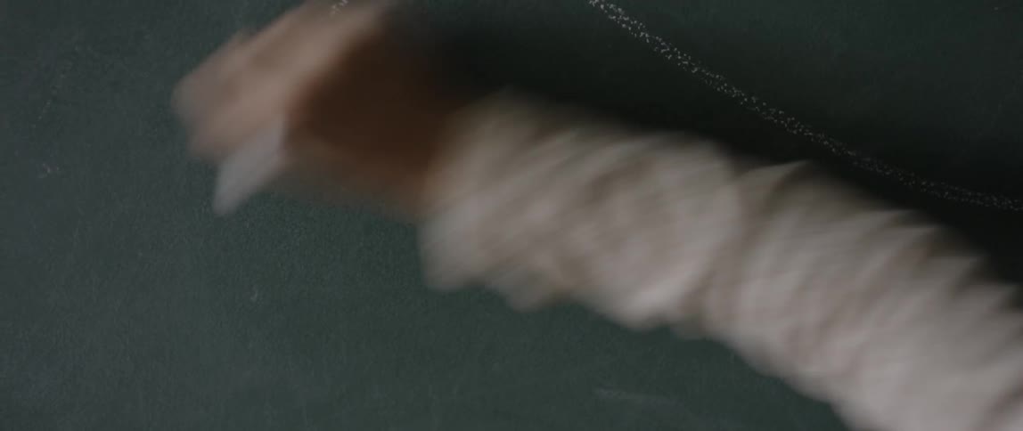 A child is using chalk to draw on a chalkboard