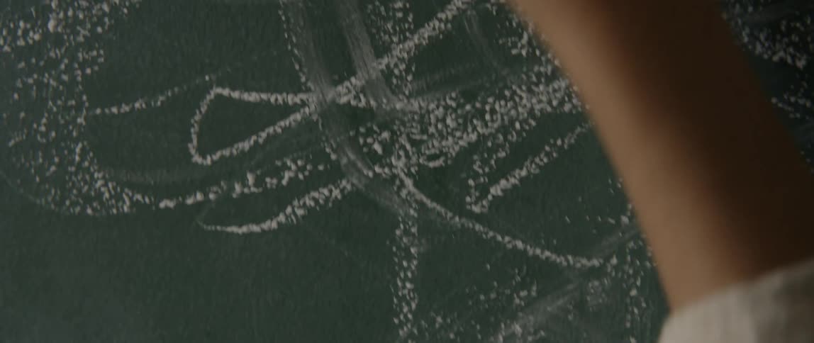 A child is drawing with chalk on a chalkboard